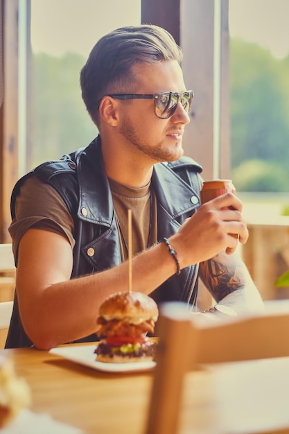 Attractive hipster dressed in leather jacket eating a vegan burger.