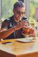 Free photo attractive hipster dressed in leather jacket eating a vegan burger.