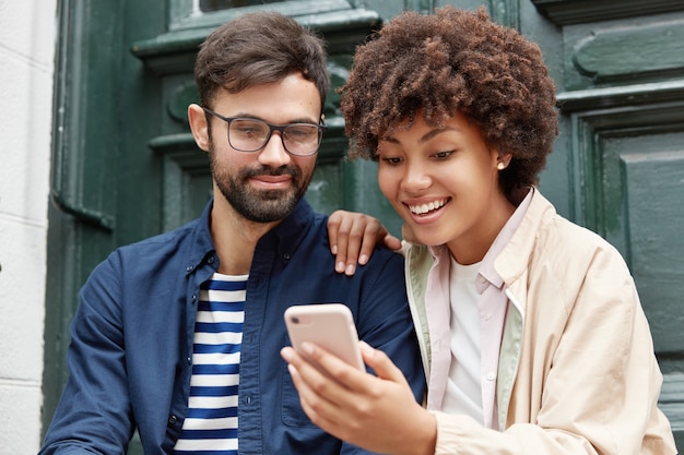 Foto gratuita attraente hipster e la sua ragazza dalla pelle scura guardano video divertenti online