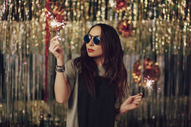 Attractive hipster woman holding sparklers in hands