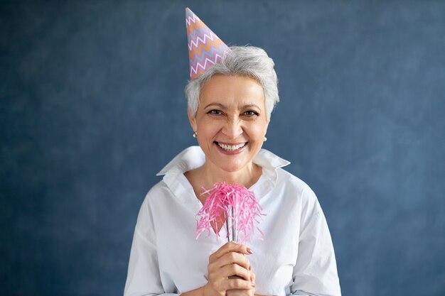 Attractive joyful mature woman with gray hair posing isolated with whistle