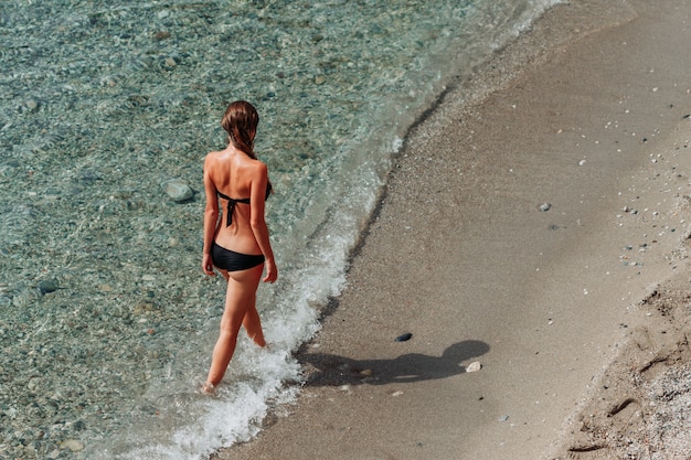 낮 동안 바다에서 걷는 여자의 비키니에 매력적인 아가씨.
