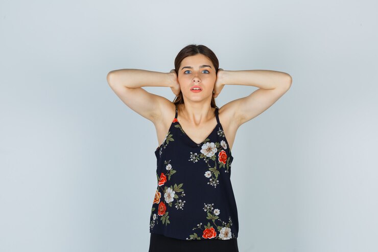 ブラウスを着て両手で耳を閉じて怖がっている魅力的な女性。正面図。