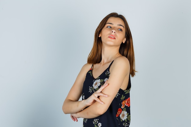 Attractive lady holding hands crossed in blouse and looking charming , front view.