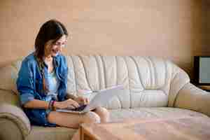 Free photo attractive lady usig laptop on leather sofa