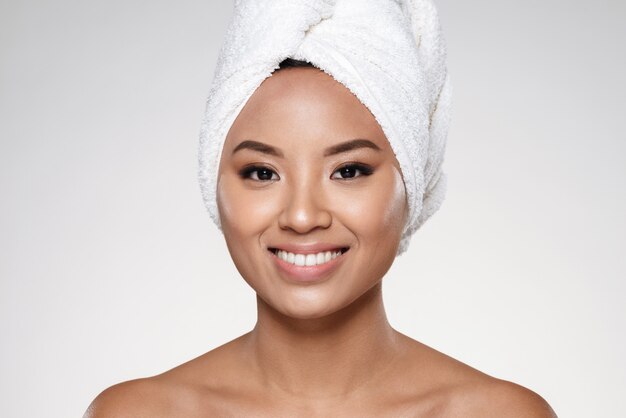 Attractive lady without make up with towel on head smiling to camera