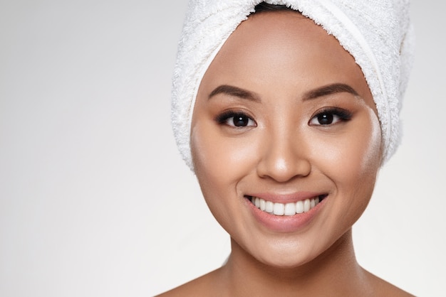 Attractive lady without make up with towel on head smiling to camera