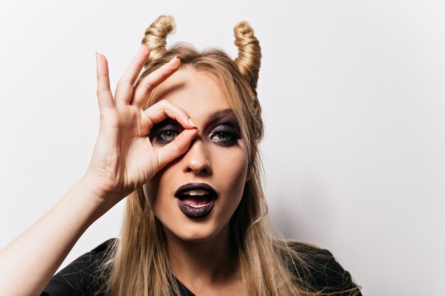 Attractive little witch posing . Inspired blonde woman preparing for carnival party.