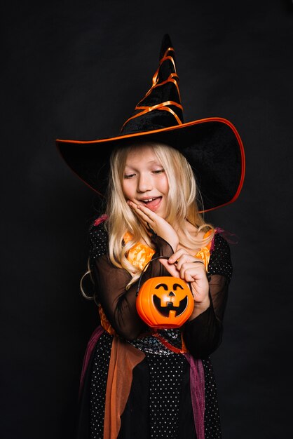 Attractive little witch with pumpkin