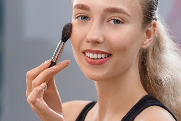 Attractive makeup artist applying tonal basis