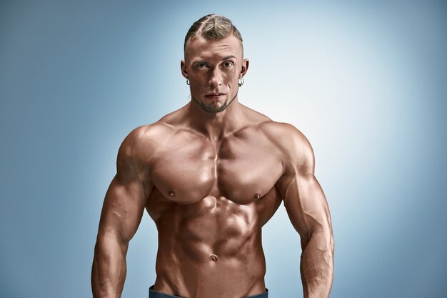 Attractive male body builder on blue wall