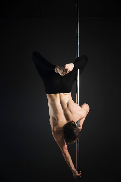 Attractive male model performing a pole dance