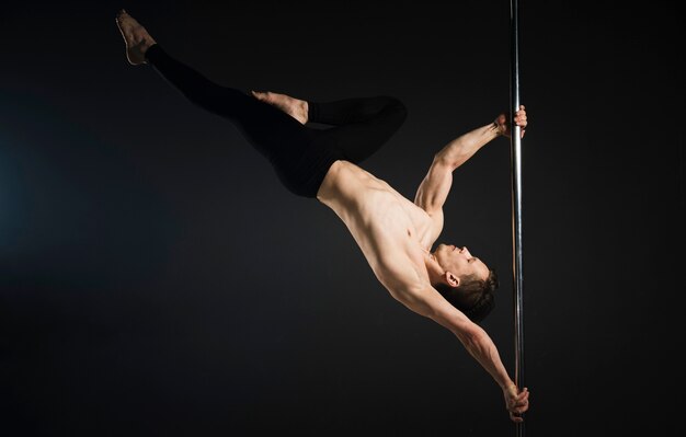 Attractive male model performing a pole dance