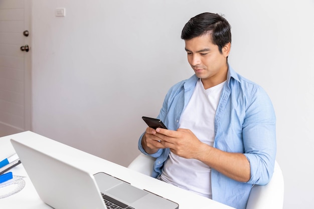 Attractive man is working at home with computer notebook and using mobile phone