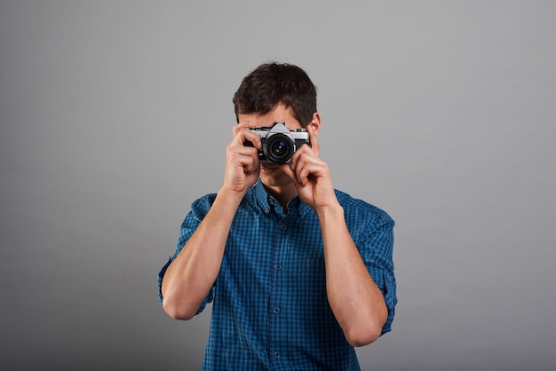 Uomo attraente che fa foto con fotocamera vintage