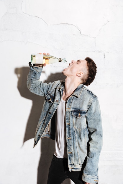Бесплатное фото Привлекательный мужчина, стоя на полу, пить алкоголь