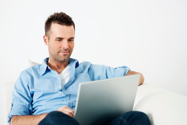 Attractive man using laptop on sofa