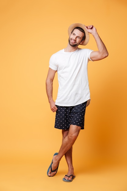 Attractive man wearing flip flops and hat looking away isolated