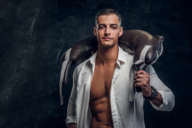 Attractive man in white opened shirt and with weight bag on his shouders is posing for photographer.