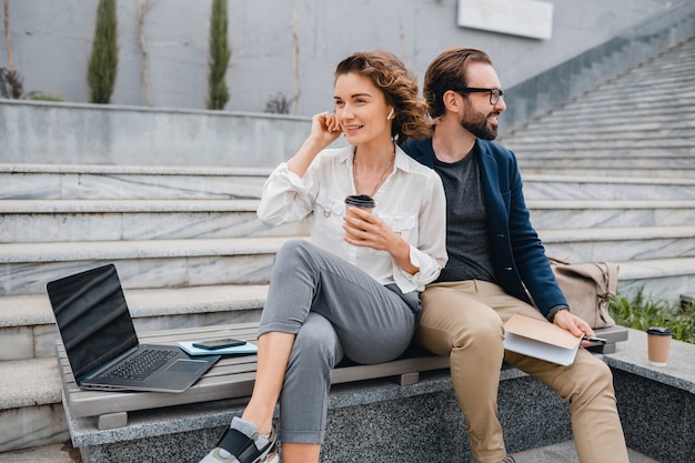 Attractive man and woman sitting on stairs in urban city center