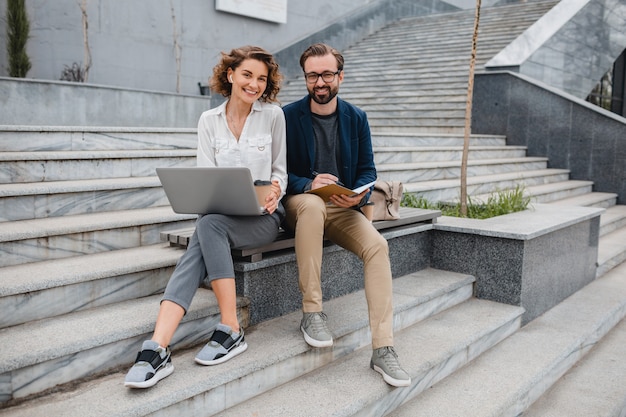 Attractive man and woman sitting on stairs in urban city center