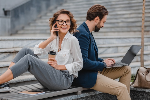 Attractive man and woman sitting on stairs in urban city center