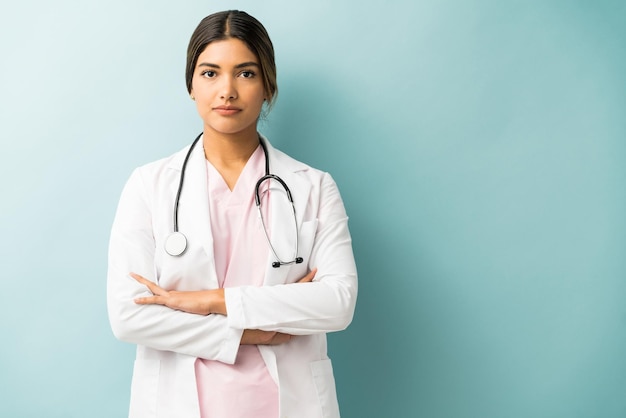 Foto gratuita attraente medico in uniforme in piedi con le braccia incrociate su sfondo isolato