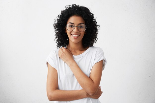 attractive mixed race female actress wearing round eyeglasses and t-shirt looking and smiling