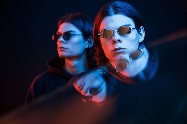 Attractive people. Portrait of twin brothers. Studio shot in dark studio with neon light