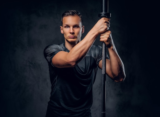 Free photo attractive power lifter holds barbell over dark grey background.