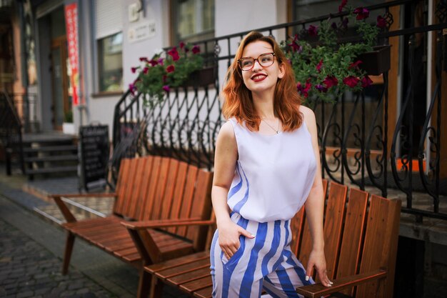 Attractive redhaired woman in eyeglasses posing at street of spring city
