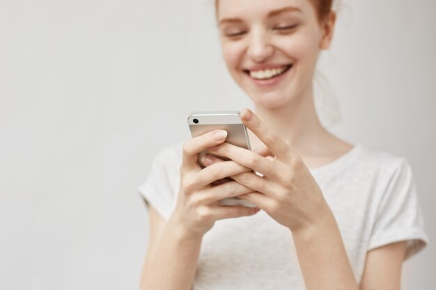 Attractive redhead woman looking ar phone smiling.
