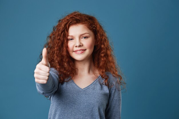Attractive redhead woman with freckles showing thumb up with happy and delightful expression. Copy space.