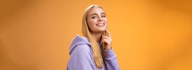 Attractive sassy selfassured caucasian blond female in purple hoodie turning camera touching chin