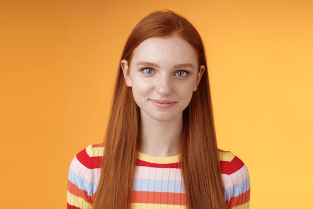 Attractive self-assured redhead girl encouraging herself look mirror confident prepare interview speech standing orange background smirking intrigued listening talking casually