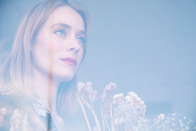 Attractive serious woman holding bouquet of dry plants behind window