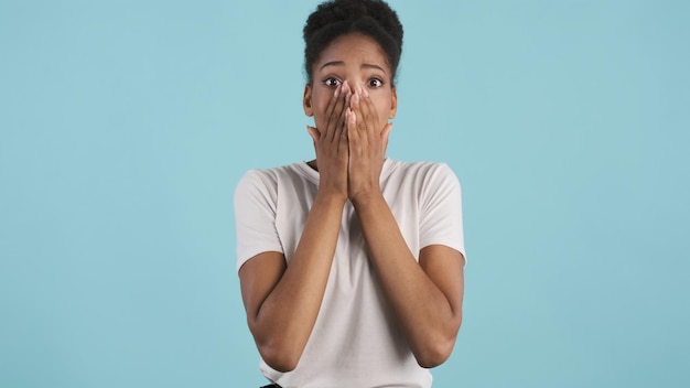 Free photo attractive shocked casual african american girl emotionally covering face with hands on camera over colorful background