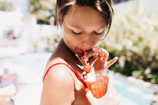 Attractive short-haired female model enjoying fruit cocktail.