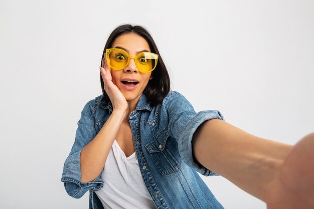 Attractive smiling excited woman making selfie photo with shocked face isolated on white