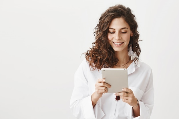 Foto gratuita imprenditore femminile sorridente attraente guardando una tavoletta digitale