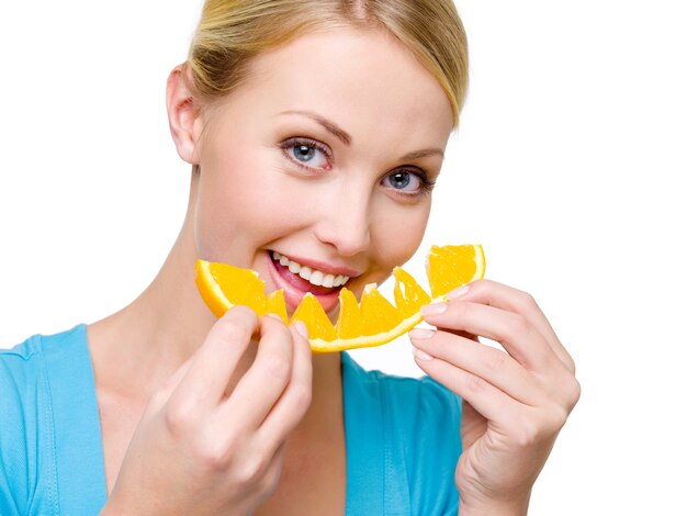 Attractive smiling woman eats the fresh orange - over white space