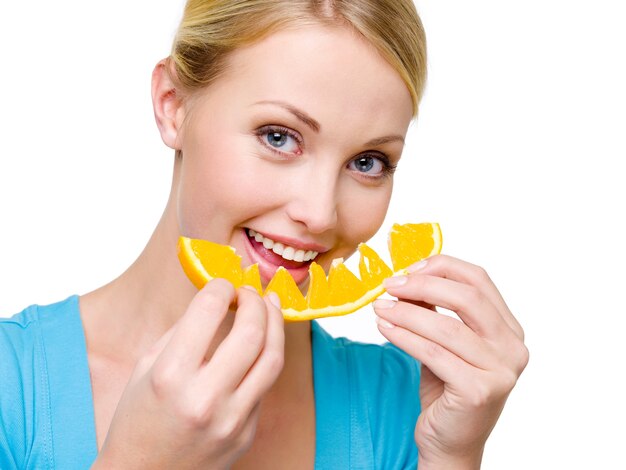 魅力的な笑顔の女性が新鮮なオレンジを食べる-白いスペースの上