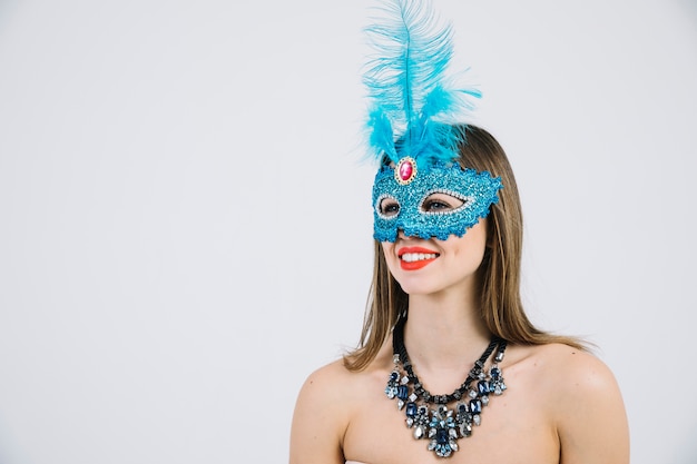 Бесплатное фото Привлекательная улыбающаяся женщина в синей карнавальной маске на белом фоне