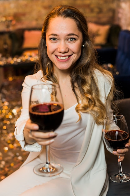 와인 한 잔을 제공하는 매력적인 웃는 여자
