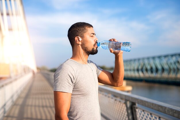 Привлекательный спортсмен пьет воду после тяжелых тренировок