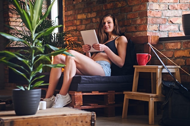 Attractive sporty female using tablet PCs and drink coffee in loft interior room.