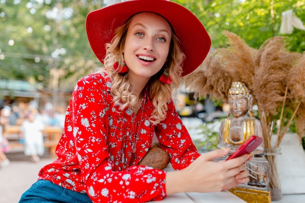 밀짚 빨간 모자와 블라우스 여름 패션 복장 스마트 폰 카페를 사용하여 들고 매력적인 세련된 금발 웃는 여자