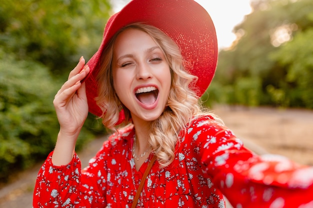 셀카를 복용 밀짚 빨간 모자와 블라우스 여름 패션 복장에 매력적인 세련된 금발 웃는 여자 photo