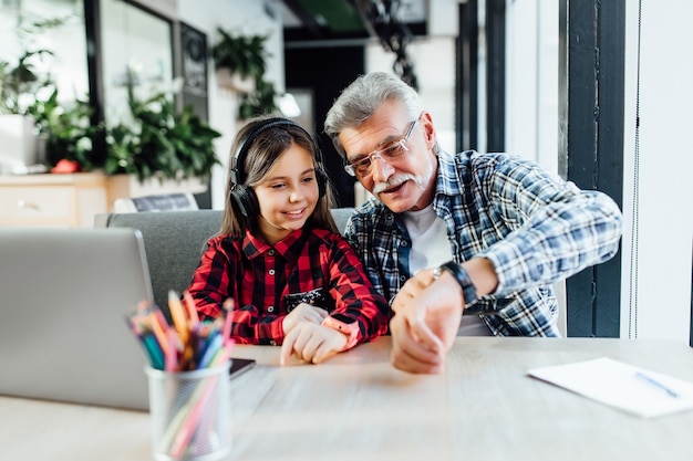 Attractive stylish short beard grandfather using smartphone with granddaughter