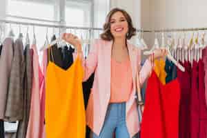Free photo attractive stylish smiling woman choosing apparel in clothing store